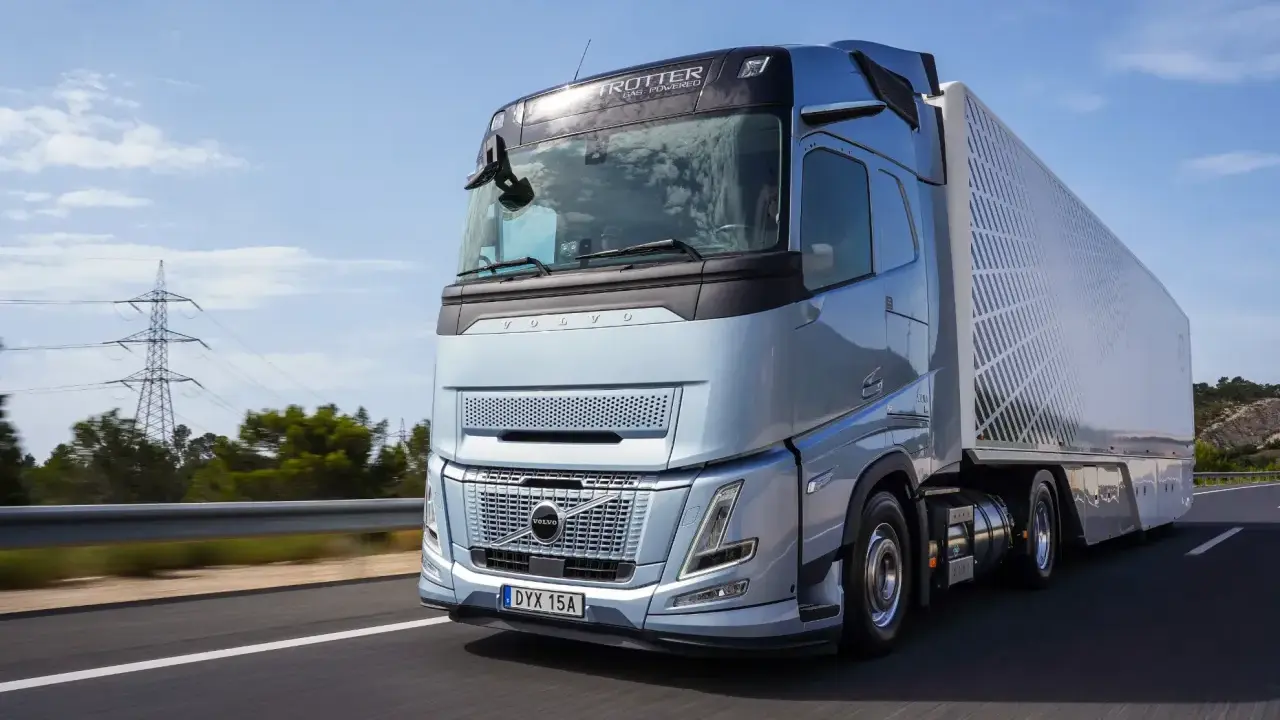 El nuevo Volvo FH Aero, un camión azul metálico, avanza por una carretera soleada, listo para transportar cargas con su diseño aerodinámico.