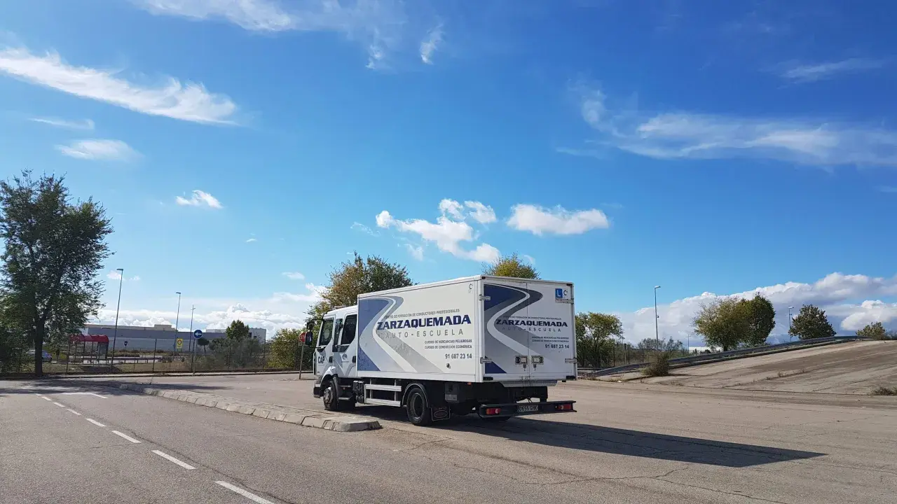 Camión de autoescuela Zarzaquemada, listo para obtener el carnet C+E. Cielo azul con nubes.