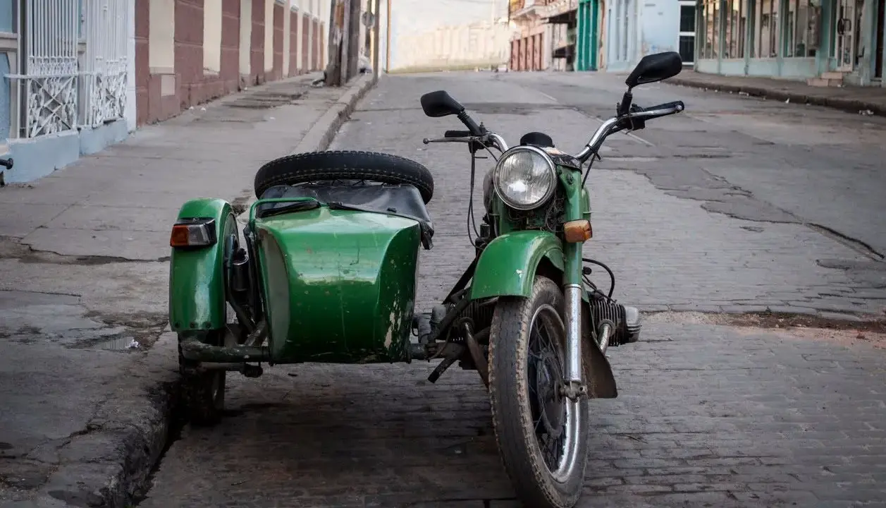 Motocicleta verde con sidecar, lista para recorrer calles empedradas. Un clásico que aún recibe permiso a motocicletas con sidecar.