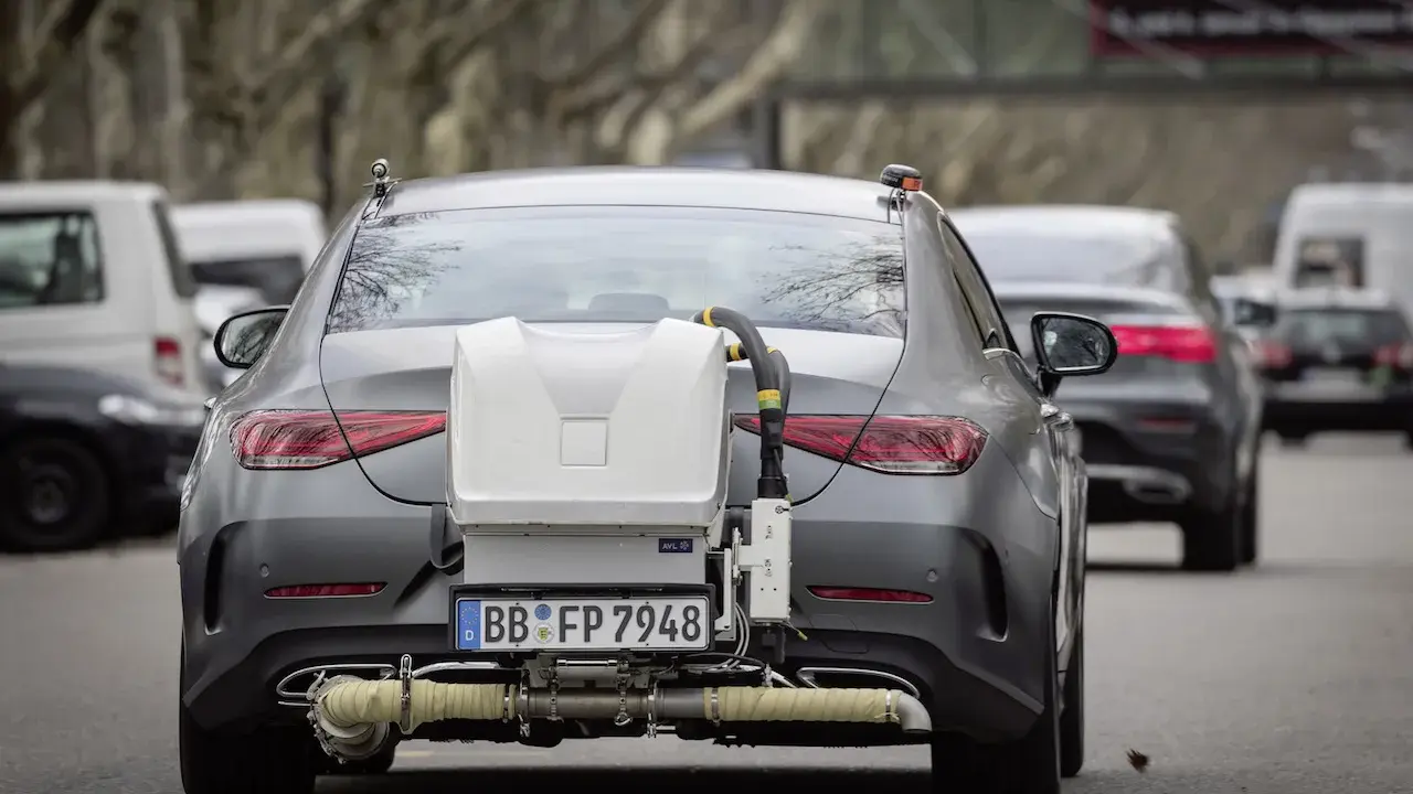 Coche gris con equipo de medición de emisiones euro 6 en la parte trasera, en pruebas de carretera.