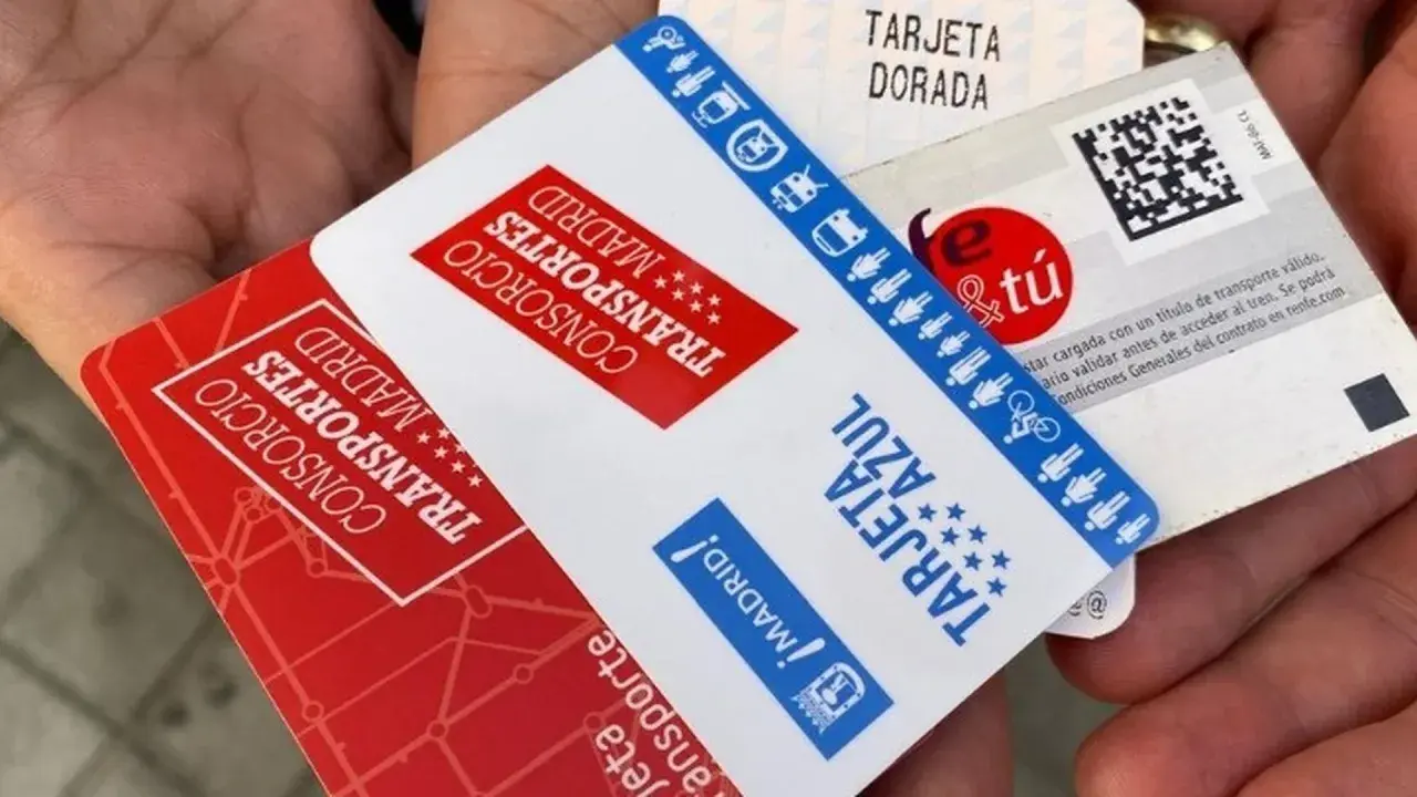 Manos sostienen varias tarjetas de transporte de Madrid, incluyendo la Tarjeta Dorada y la Tarjeta Azul, mostrando algunas excepciones de transporte.