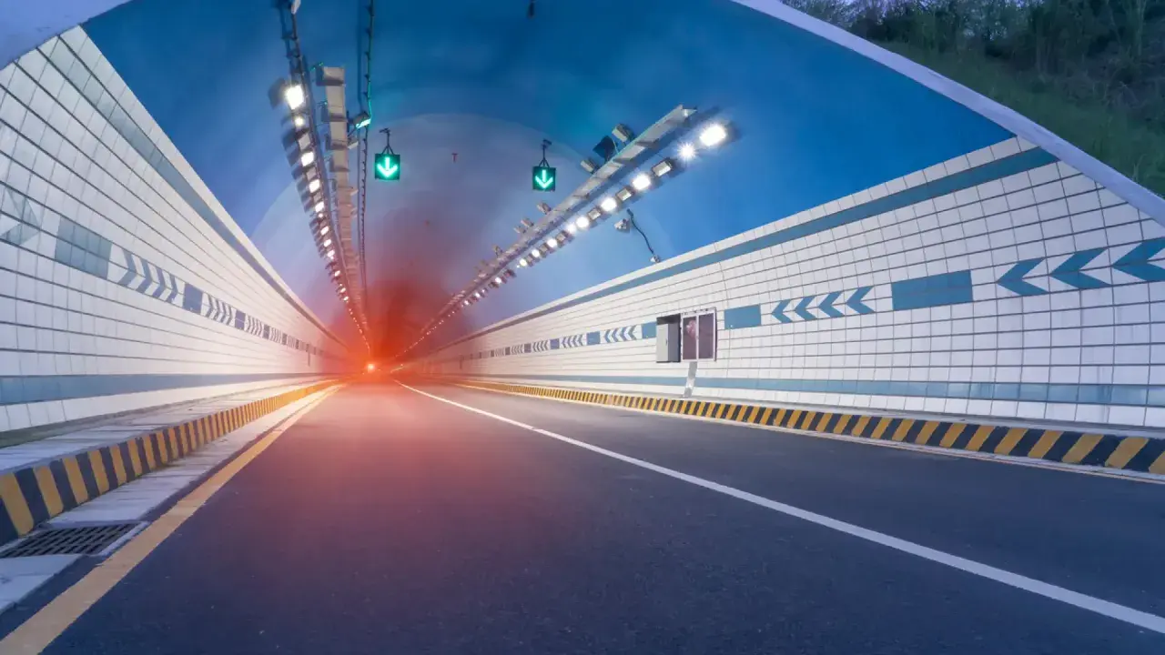 El efecto túnel se percibe al entrar en este túnel vial iluminado, con luces verdes y un resplandor rojo al fondo.