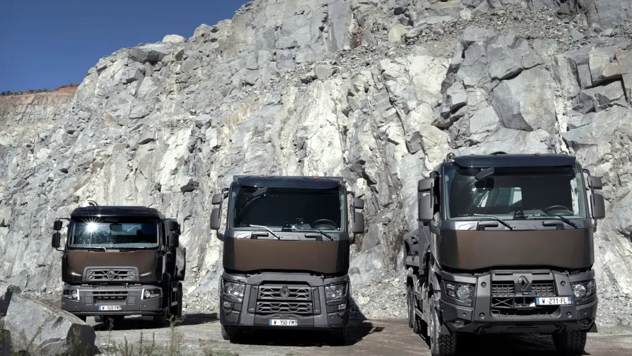 Tres robustos renault trucks modelos posan ante un imponente acantilado de cantera, listos para el trabajo pesado.