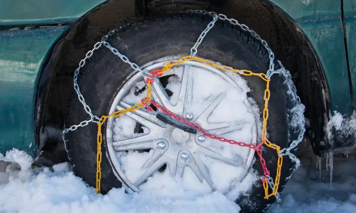 Neumático con cadenas de nieve instaladas, mostrando cómo se ponen las cadenas de nieve para circular en condiciones invernales.
