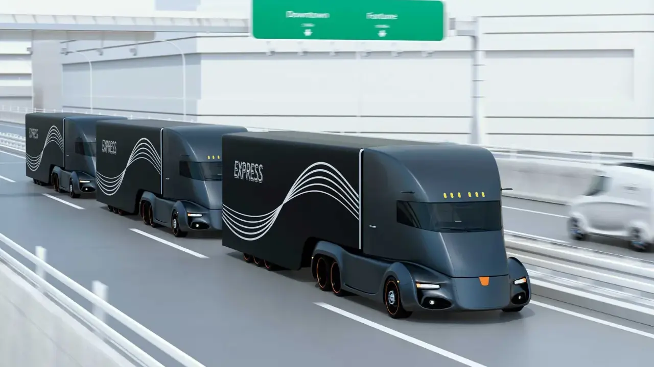 Tren de camiones del futuro, negros y aerodinámicos, circulando por una autopista.
