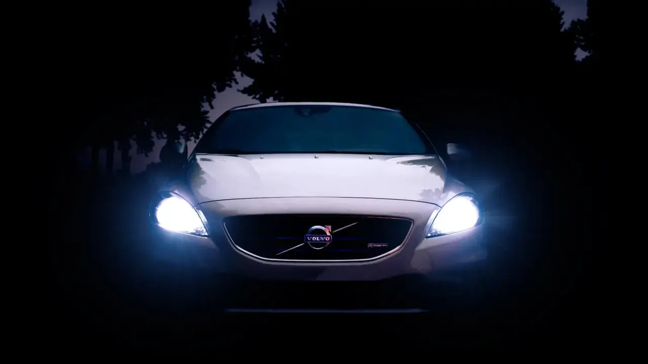 Volvo blanco con luces encendidas en la oscuridad.