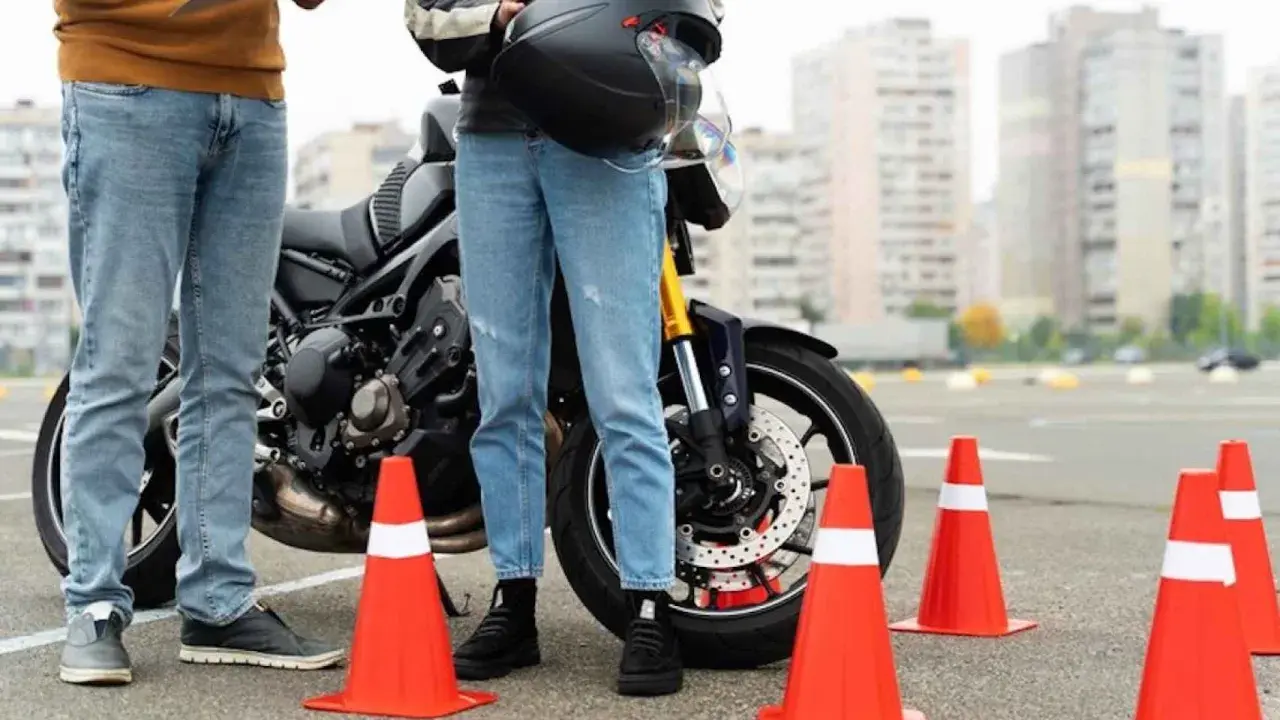 Persona se prepara para el circuito examen moto a1. Un instructor revisa una lista junto a una moto y conos naranjas.