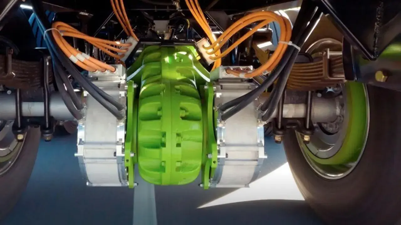 Detalle del sistema de freno eléctrico de camiones, con componentes verdes y naranjas, y cables negros.
