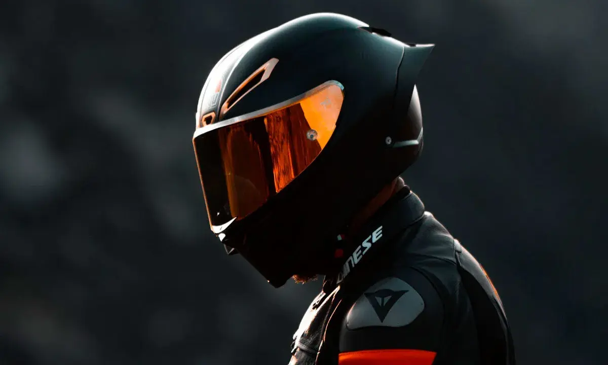 Motociclista con casco negro y visor naranja, listo para la acción. El uso obligatorio de casco es clave para la seguridad.
