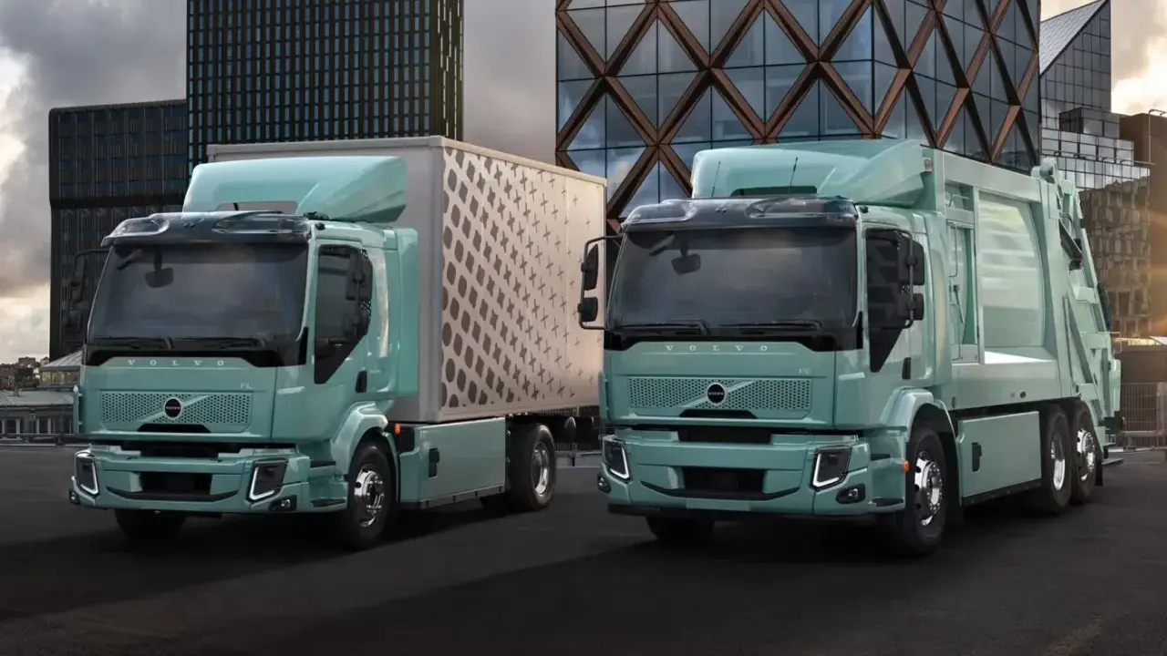 Dos camiones Volvo FE Electric, uno con caja y otro compactador, lucen modernos frente a edificios urbanos.