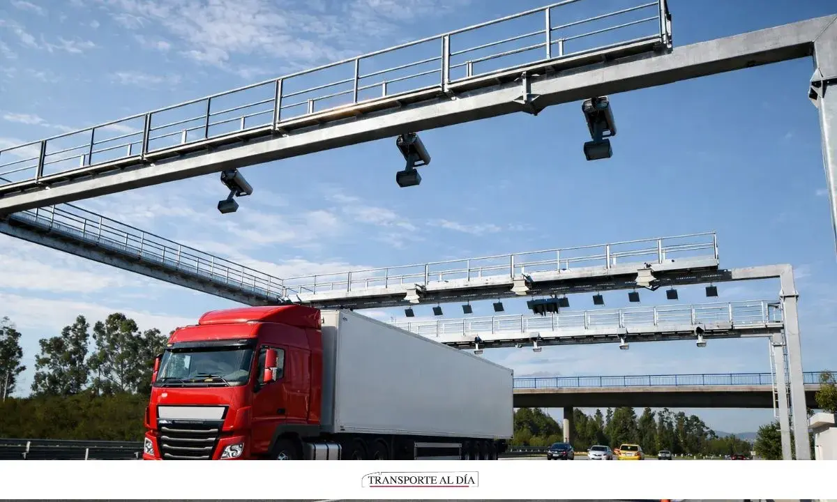 Camión rojo pasa por pórtico de peaje electrónico, similar a los de euroviñeta en Luxemburgo y Holanda.