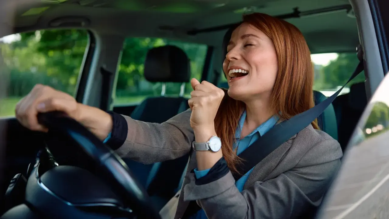 Mujer sonríe y canta al volante, feliz de conducir en España con su carnet de conducir ucraniano.