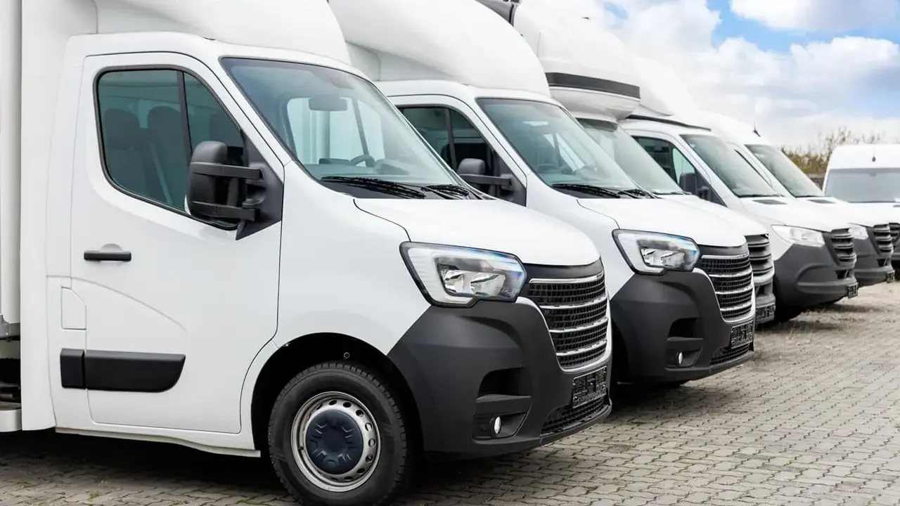 Fila de furgonetas blancas listas para la entrega. El modelo dgt n1 es el primero de la fila, con un diseño moderno y robusto.