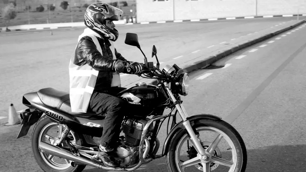 Motociclista con casco y chaleco reflectante en una Honda, preparándose para obtener el carnet de moto grande.