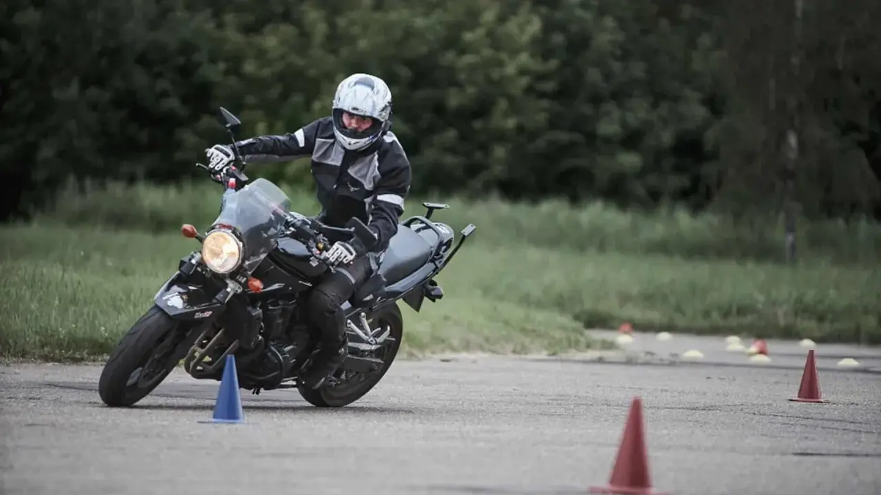 Persona con casco y equipación de moto practica maniobras en circuito con conos. Averigua el carnet de moto a1 precio.