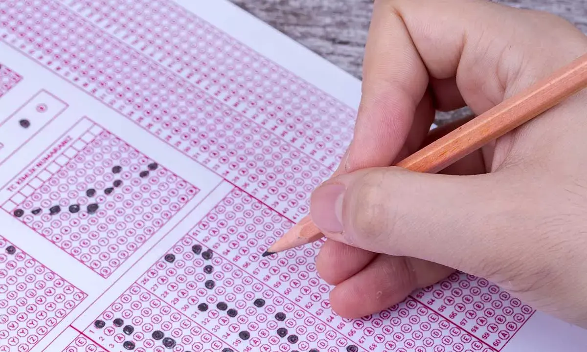 Mano con lápiz completando un examen de respuestas múltiples. ¿Cuántas preguntas son el examen de conducir?