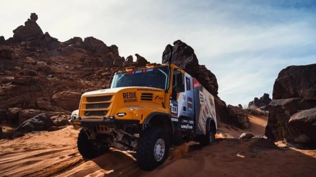 Camión Iveco Dakar amarillo compitiendo en un terreno desértico rocoso y arenoso, levantando polvo.