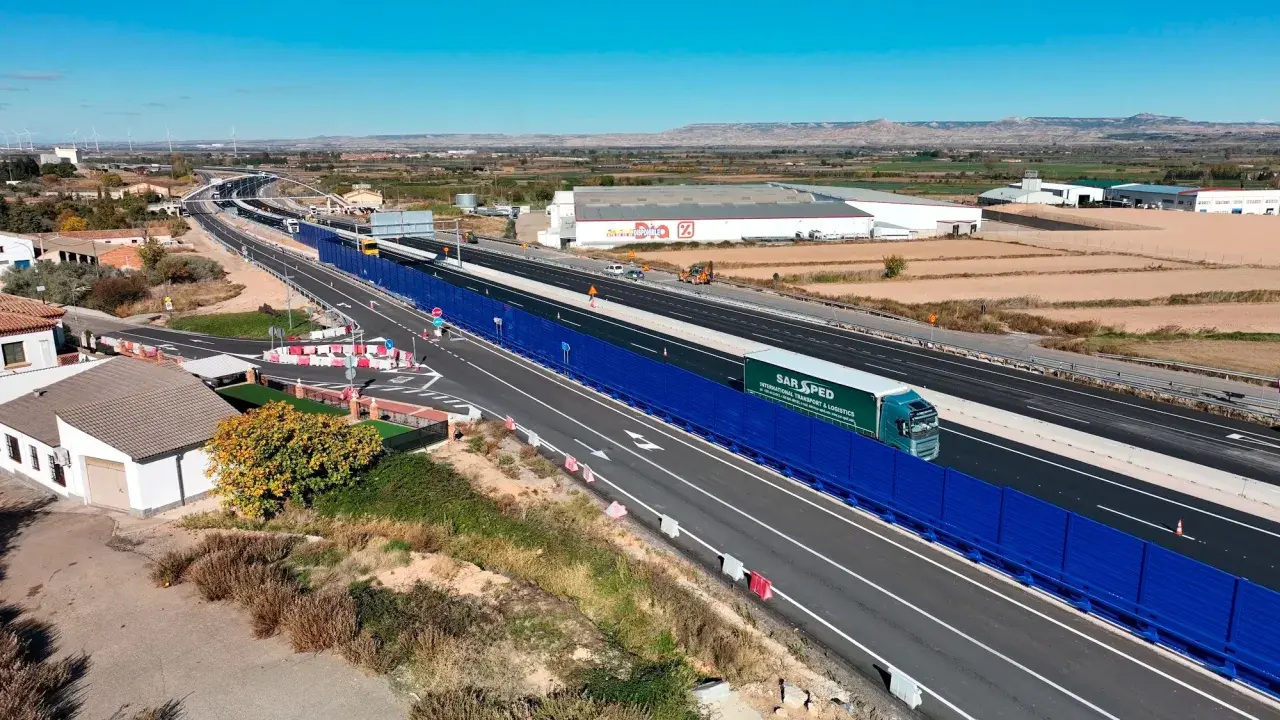 Camión de SAR SPED circula por la a68 autovía, con barreras acústicas azules y paisaje rural al fondo.