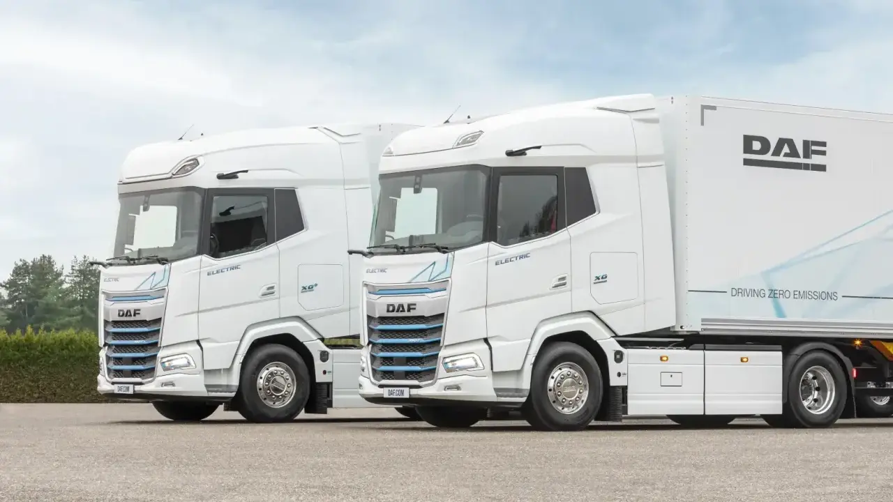Dos camiones DAF XG Plus eléctricos, blancos, con el interior visible. Uno lleva un remolque DAF.