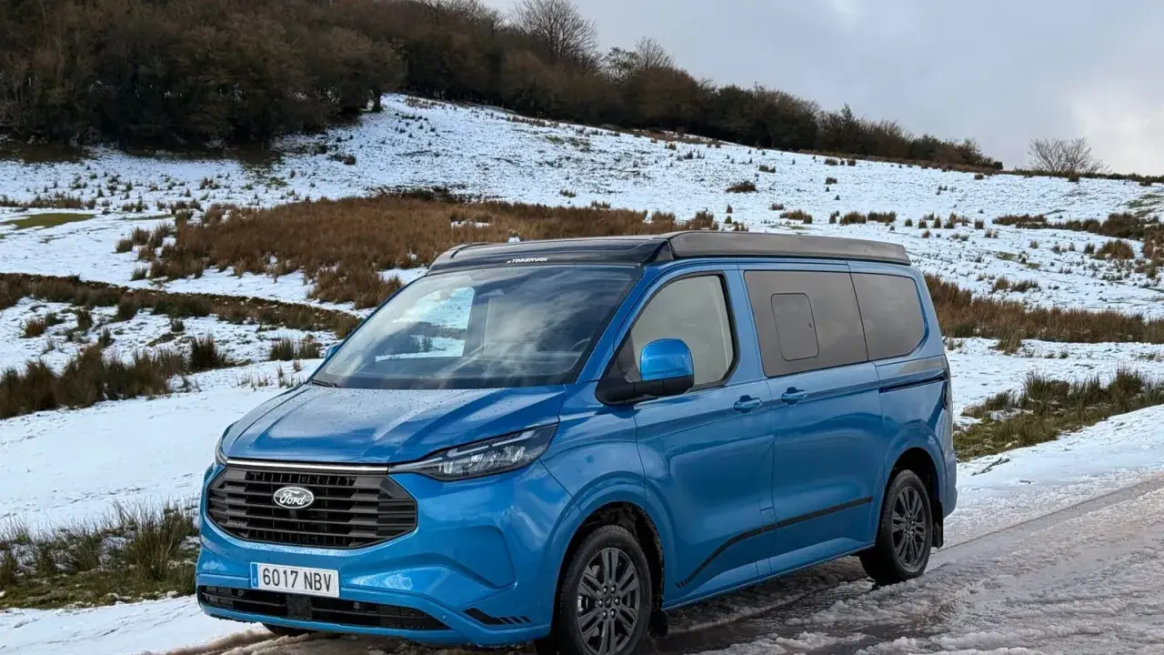 Furgoneta phev azul aparcada en un camino nevado, lista para una aventura invernal.