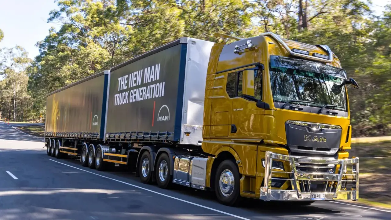 Camión amarillo brillante de MAN en carretera, con el lema "The New MAN Truck Generation". Ideal para mostrar que pueden circular los camiones los domingos.