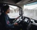 Interior de un camion Volvo. Un hombre con gafas conduce, observando las cámaras de visión.