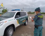 Agente de la Guardia Civil anota datos junto a un vehículo oficial. Se pregunta qué carnet se necesita para conducir un minibus.