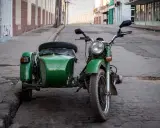 Motocicleta verde con sidecar, lista para recorrer calles empedradas. Un clásico que aún recibe permiso a motocicletas con sidecar.