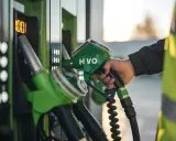 Mano con boquilla HVO verde, lista para la declaración de gasóleo profesional. El surtidor muestra 100.