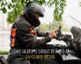Persona con casco y chaqueta de moto ajustando su móvil en el manillar. ¿Cuánto se tarda en sacar el carnet de moto A2?