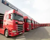 Una fila de camiones Scania rojos, listos para la acción, con el logo de Scania en el edificio.
