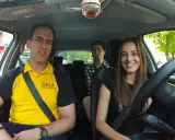 Instructor de autoescuela sonríe junto a dos alumnos en un coche. ¡Listos para el turismo y el aprendizaje!