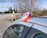 Baliza de emergencia roja y blanca en el techo de un coche plateado, lista para evitar una multa.