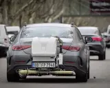 Coche gris con equipo de medición de emisiones euro 6 en la parte trasera, en pruebas de carretera.