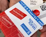 Manos sostienen varias tarjetas de transporte de Madrid, incluyendo la Tarjeta Dorada y la Tarjeta Azul, mostrando algunas excepciones de transporte.