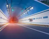El efecto túnel se percibe al entrar en este túnel vial iluminado, con luces verdes y un resplandor rojo al fondo.