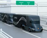 Tren de camiones del futuro, negros y aerodinámicos, circulando por una autopista.