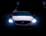 Volvo blanco con luces encendidas en la oscuridad.