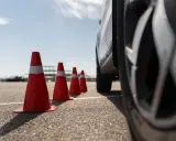 Conos naranjas marcan la zona f para el carnet C. Un coche se acerca, listo para la maniobra.