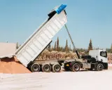 Camión volquete descargando arena. La distancia entre ejes de los camiones es clave para su maniobrabilidad en terrenos difíciles.