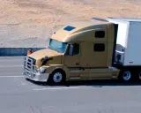 Camión dorado de 40 toneladas en carretera, transportando carga en su remolque blanco.
