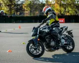Motociclista con equipo de protección en una pista de examen con conos.