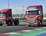 Dos camiones Iveco rojos, uno antiguo y otro moderno, en una pista de carreras.