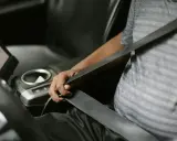 Persona se abrocha el cinturón de seguridad en un coche moderno. Las normativas de tráfico exigen que todos los pasajeros, a menos que estén exentos de llevar cinturón de seguridad, lo usen.