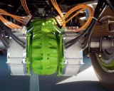 Detalle del sistema de freno eléctrico de camiones, con componentes verdes y naranjas, y cables negros.
