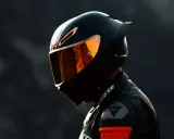 Motociclista con casco negro y visor naranja, listo para la acción. El uso obligatorio de casco es clave para la seguridad.