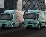 Dos camiones Volvo FE Electric, uno con caja y otro compactador, lucen modernos frente a edificios urbanos.