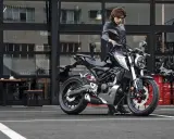 Joven con chaqueta de cuero junto a una moto negra, listo para obtener su a1 permiso de conducir.