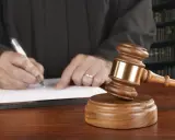 Juez firma sentencia que implica retirada carnet de conducir por curso. Martillo de juez y libros de derecho.