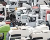 Desguace de camiones. Se aprecian cabinas blancas y verdes, algunas con partes oxidadas, listas para cumplir los requisitos de achatarramiento de camiones.